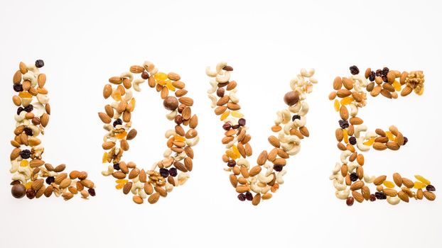 The word love laid out from a mix of nuts on a white background. Healthy lifestyle concept.