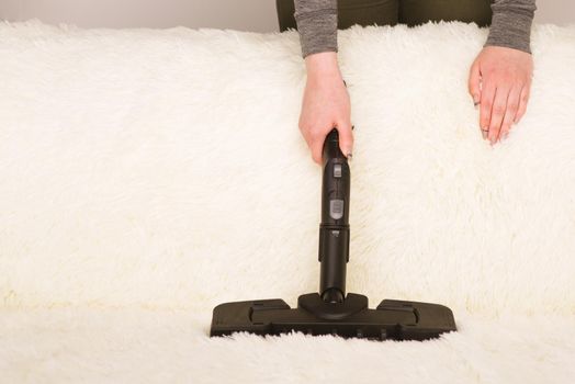 Young woman with a steam cleaner cleans the carpet on the couch - Image