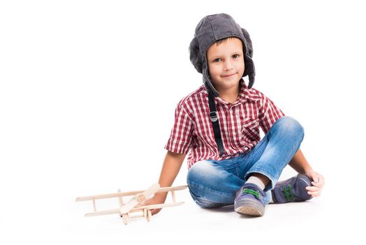 little boy with pilot hat and toy airplane sitting isolated on white background