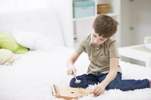 A child with a musical instrument. Boy learn to play dulcimer