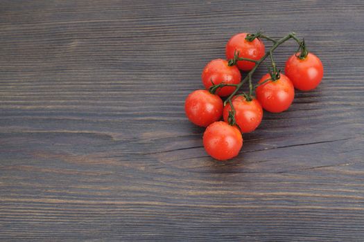 Ripe cherry tomatoes on a twig on a dark woden background - image