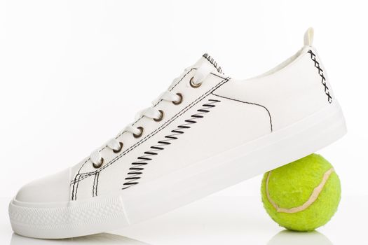 Fashionable white walking shoes with tennis ball on a white background. - image