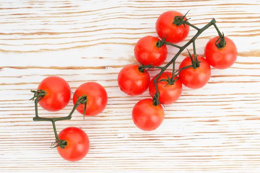 Ripe cherry tomatoes on a twig on a white woden background close up - image