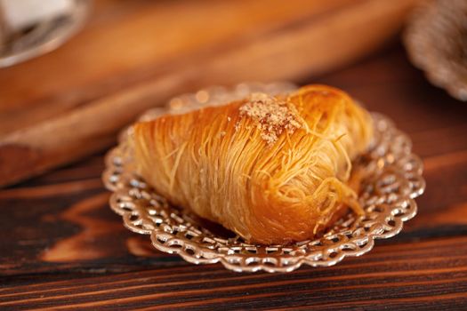 Turkish sweets on small plate on brown wooden background, close up