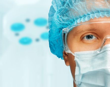 Young man surgeon in cap, glasses and mask looks at camera