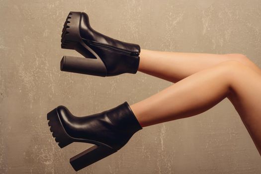 beautiful female feet in ankle boots near wall