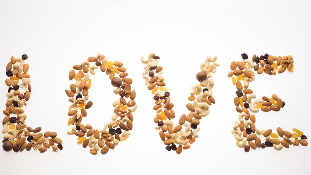 The word love laid out from a mix of nuts on a white background. Healthy lifestyle concept.
