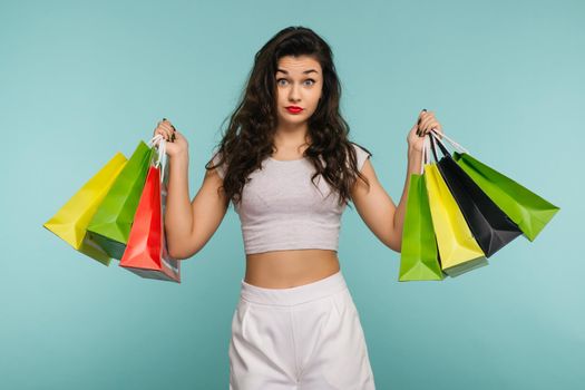 Black Friday Concept. Close-up portrait of young beautiful woman holding Shopping bags, looking at camera, isolated on blue background