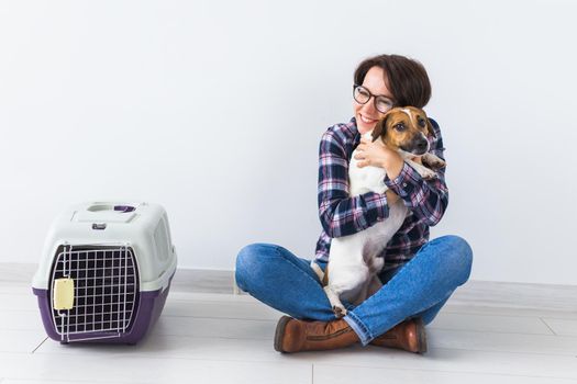 Dog carrying bags and pets owner concept - Attractive cheerful female in plaid shirt holds favourite pet. Happy woman with her jack russell terrier.