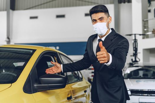 Man car dealer wearing protective medical mask on his working place, coronavirus prevention concept