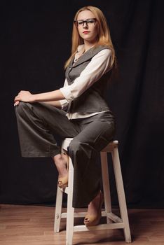 young businesswoman sitting on the chair over dark background.