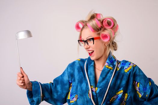 Screaming crazy housewife in a dressing gown and curlers with a ladle in her hand.