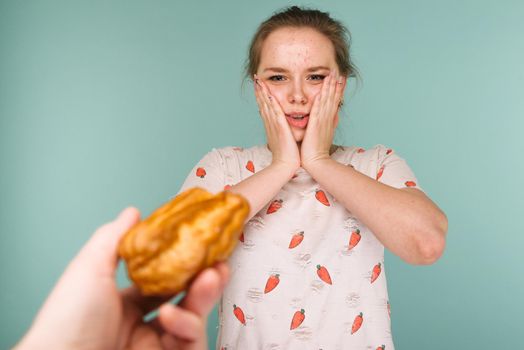 Portrait of pimply teen girl hows hands stop on a delicious cake on blue background