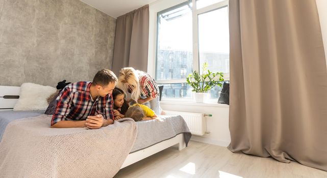 happy family mother, father and two children playing and cuddling at home