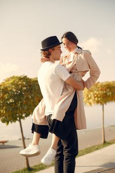 Couple by the water. Guy in a black hat. Pair on a sunset background. People dances.