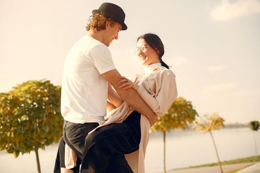 Couple by the water. Guy in a black hat. Pair on a sunset background. People dances.