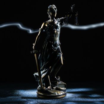 Themis statuette stands on the old vintage stone table. Picture taken with a light brush - Image