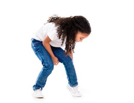 cute little girl with curls and dark skin bent down to fix shoes isolated on white background