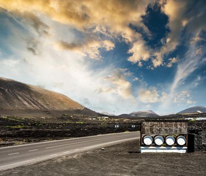 road and restaurant advertisement casks near mountains against sunset sky in Lanzarote, Canary Islands, Spain
