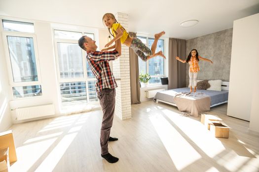 happy father and two children playing and cuddling at home on floor