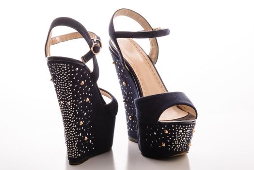 Stylish women&#39;s blue sandals with high heels with studs on a white background.