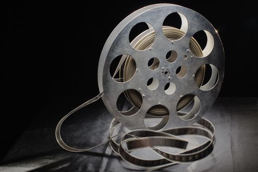 reel of film standing on a black table with black background