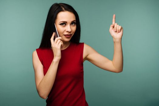 beautiful caucasian surprised young girl talking on her cell phone pointing up isolated background - Image