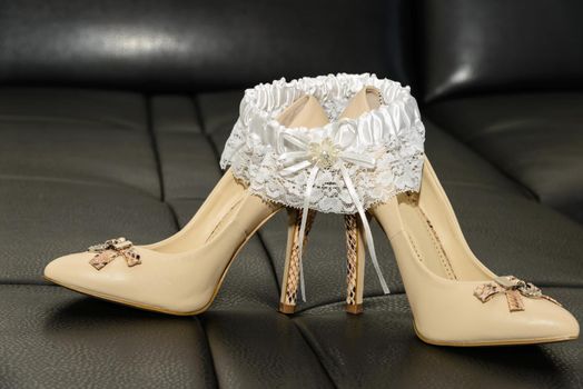 Garter of the bride shoes on a leather couch.
