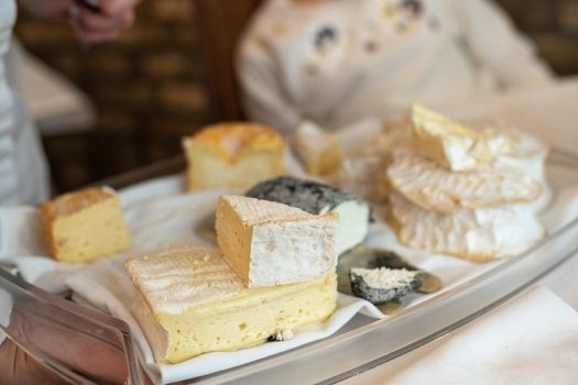 The waiter holds a plate with French Normandy cheeses