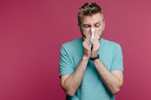 studio picture from a young man with handkerchief. Sick guy isolated has runny nose. man makes a cure for the common cold