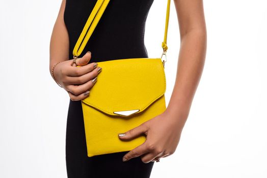 Fashion girl. Young woman posing in black dress and yellow bag .