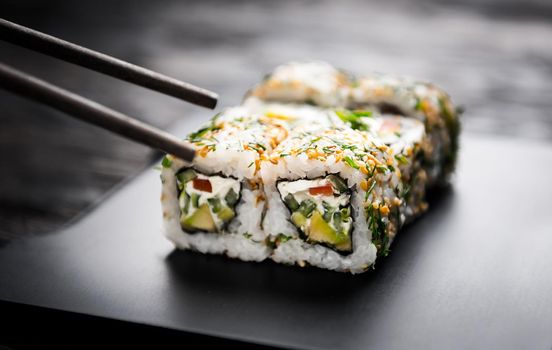 closeup of sushi rolls with vegetable filling on black tray