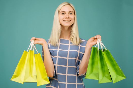 Happy girl in a checkered blouse holds shopping bags on blue background