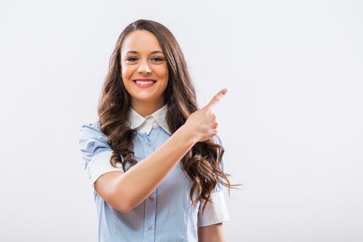 Image of beautiful businesswoman pointing on gray background.