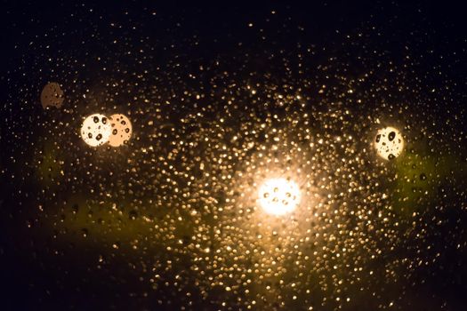 Drops of rain on window glass, lanterns in the background -image