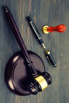 Judge's gavel, fountain pen and a stamp on an old wooden table - Image
