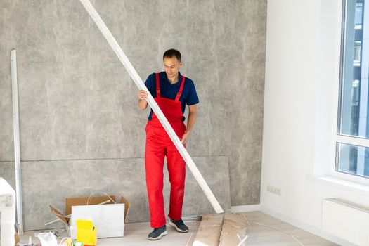 Rear back behind view photo of unrecognizable repairman master using rule to measure the required width of drywall and put label mark