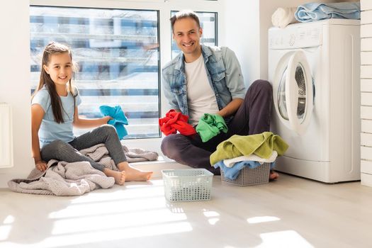 Happy family man father householder and child daughter in laundry with washing machine