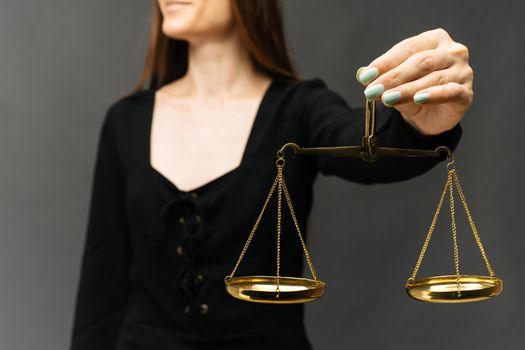 Serious woman holding the justice scale on dark background - image