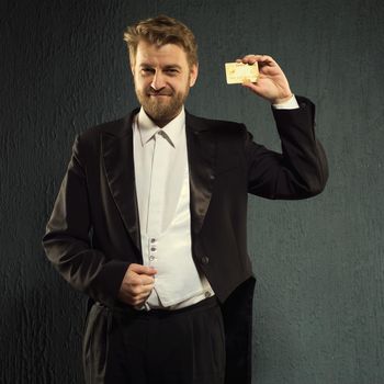 Positive man in a tailcoat offers a credit card. - image