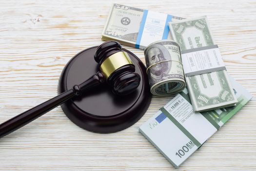 Top view Judge's gavel and packs of dollars and euro banknotes on a white wooden table.The concept of growing national debt- image