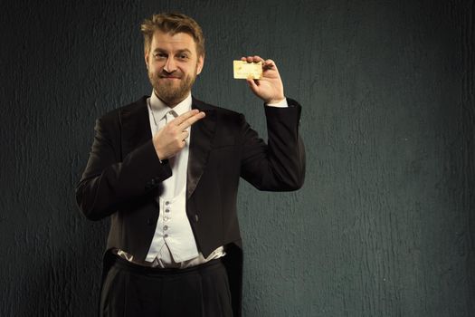 Positive man in a tailcoat pointing finger to the credit card. - image