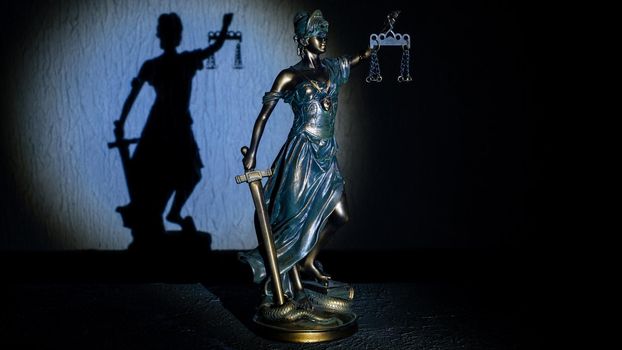 Themis statuette stands on the old vintage stone table. Picture taken with a light brush - Image
