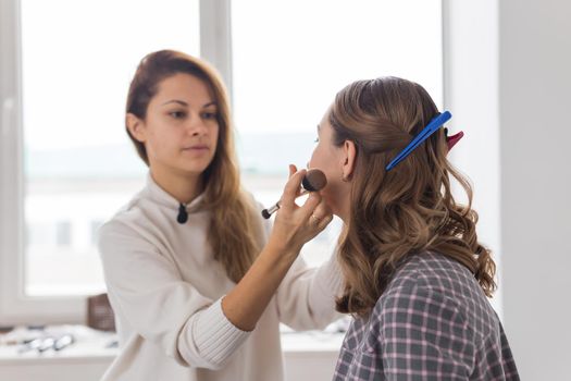 Beauty and cosmetics concept - Makeup artist doing professional make up of young woman.