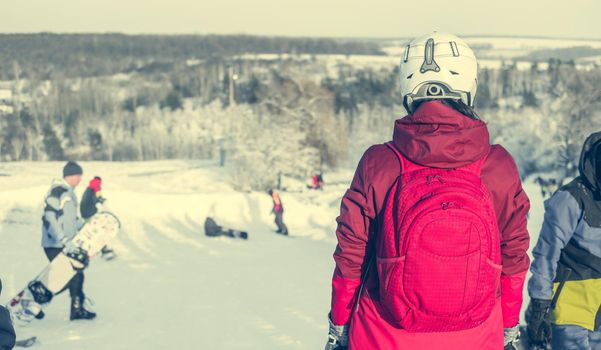 girl in ski suit on a snowhill view from back