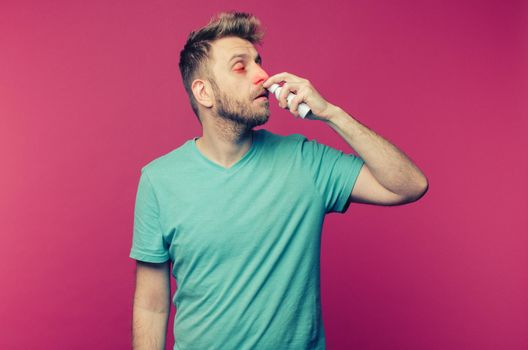 studio picture from a young man uses nose spray. Sick guy isolated has runny nose. man makes a cure for the common cold. toned