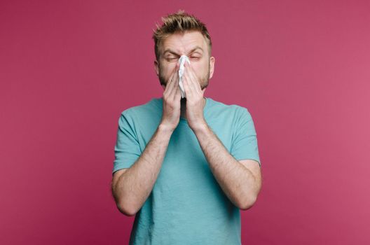 studio picture from a young man with handkerchief. Sick guy isolated has runny nose. man makes a cure for the common cold