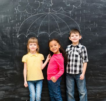 three funny laughing children with umbrella drawn on the blackboard on backgorund