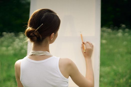 woman artist in aprons in nature draws a picture art. High quality photo