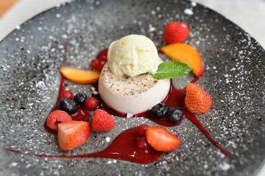 A panna cotta at a restaurant on a black plate